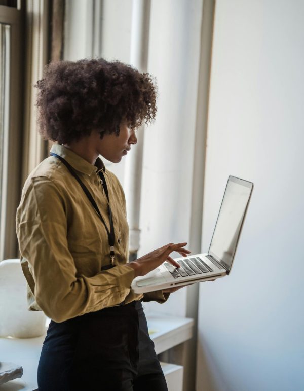 Side profile of a businesswoman using a laptop in a well-lit office environment.